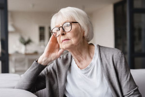 A woman sits on a sofa, looking concerned.